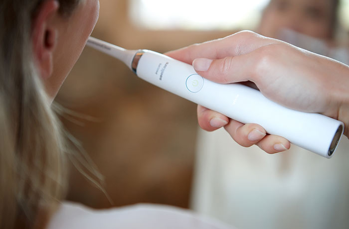 N&aelig;rbillede af en kvinde, der b&oslash;rster sine t&aelig;nder med en hvid Sonicare-eltandb&oslash;rste fra Philips.
